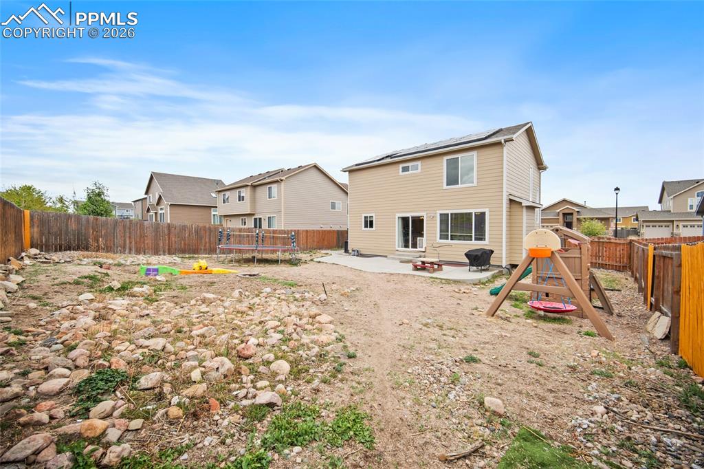 Image 36 of 43: Expansive backyard featuring a full perimeter wooden fence, a concrete pati