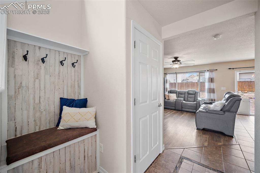 Image 4 of 43: Entryway built-in bench with hooks, wood-finish flooring, and an open conce