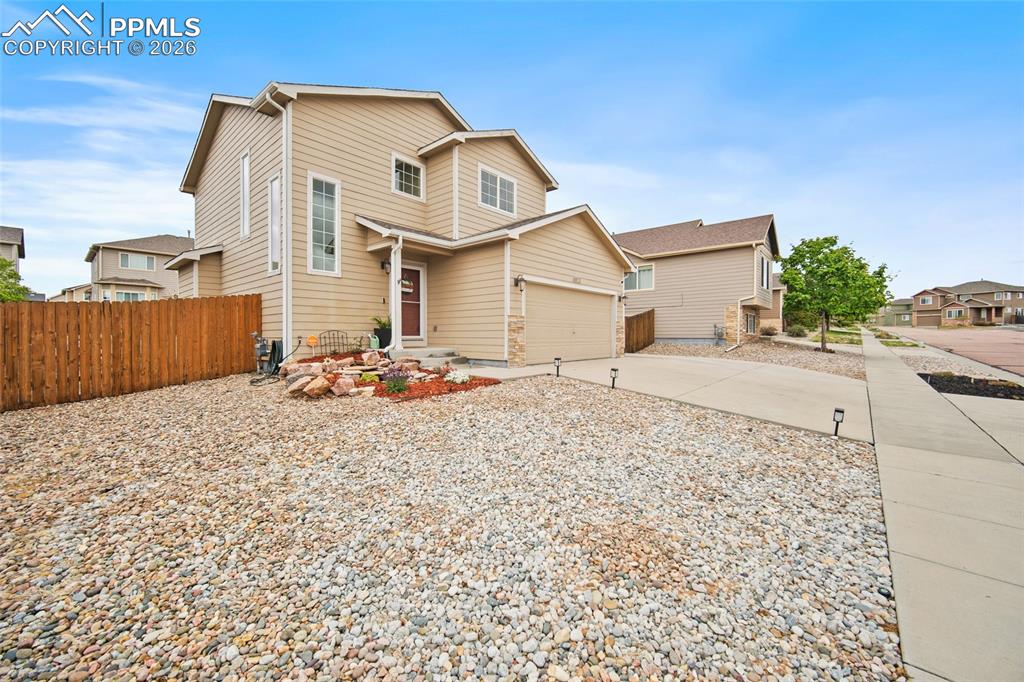 Image 40 of 43: Two-story residence featuring light beige siding and a prominent front entr