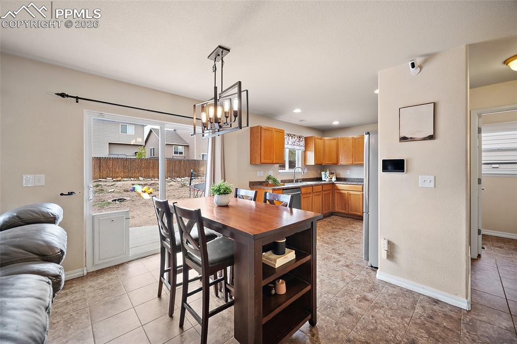 Image 5 of 43: Kitchen and dining area featuring warm wood-finish cabinetry, tile flooring