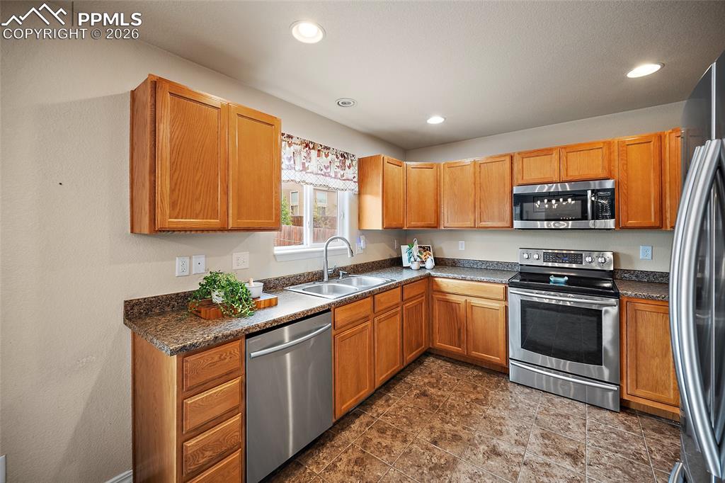 Image 7 of 43: Kitchen with wood cabinetry, stainless steel appliances, and L-shaped count