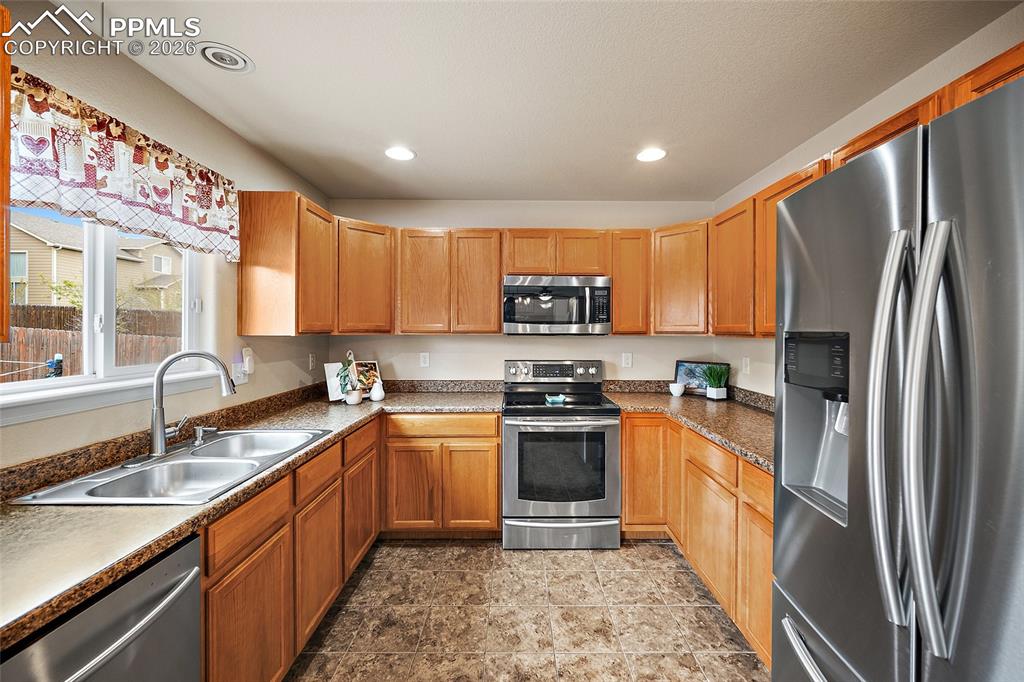 Image 8 of 43: Kitchen featuring wood cabinetry, stainless steel appliances, speckled coun
