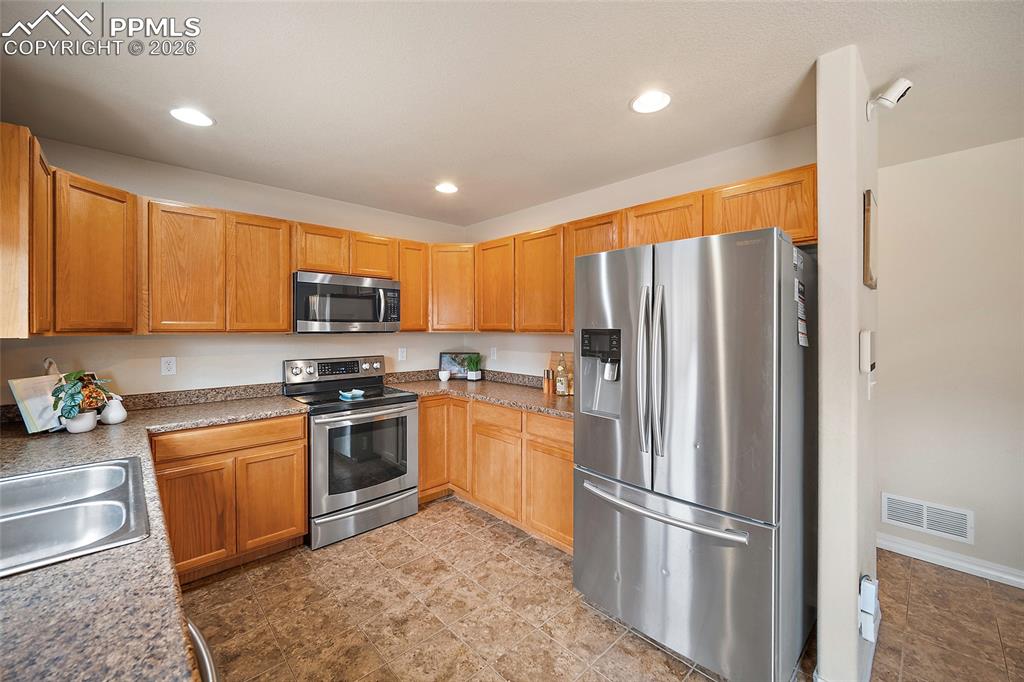 Image 9 of 43: Well-appointed kitchen featuring light wood cabinetry, stone-finish counter