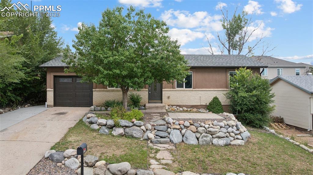 Caption: View of front of home featuring brick siding, a shingled roof, concrete driveway, and a garage