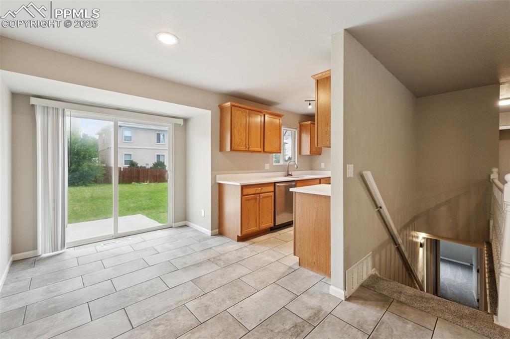 Image 10 of 37: Kitchen featuring light countertops, dishwasher, brown cabinetry, light til