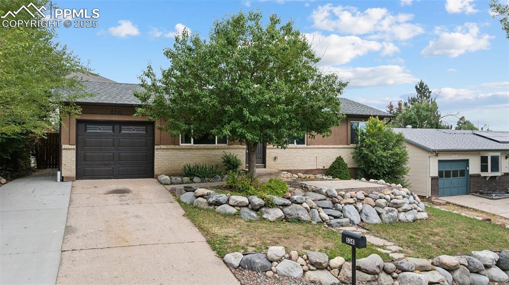 Image 2 of 37: View of property hidden behind natural elements with brick siding, an attac