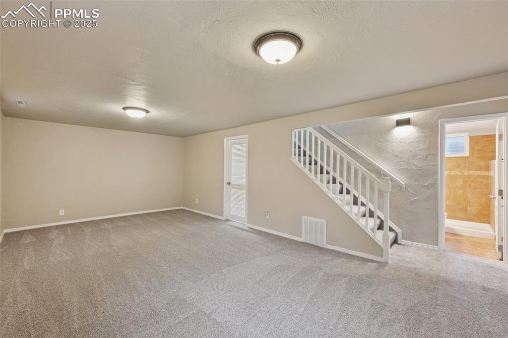 Image 20 of 37: Basement featuring stairs, carpet floors, and a textured ceiling