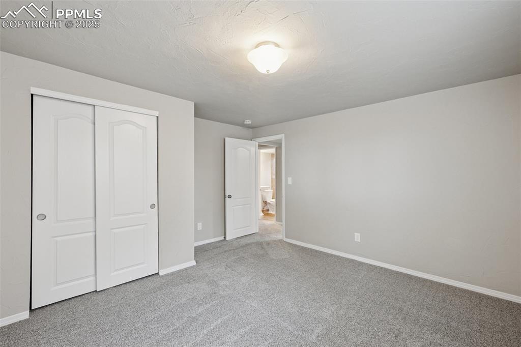 Image 25 of 37: Unfurnished bedroom with carpet floors, a closet, and a textured ceiling