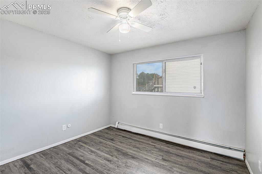 Image 10 of 18: Empty room featuring a baseboard radiator, a textured ceiling, wood finishe