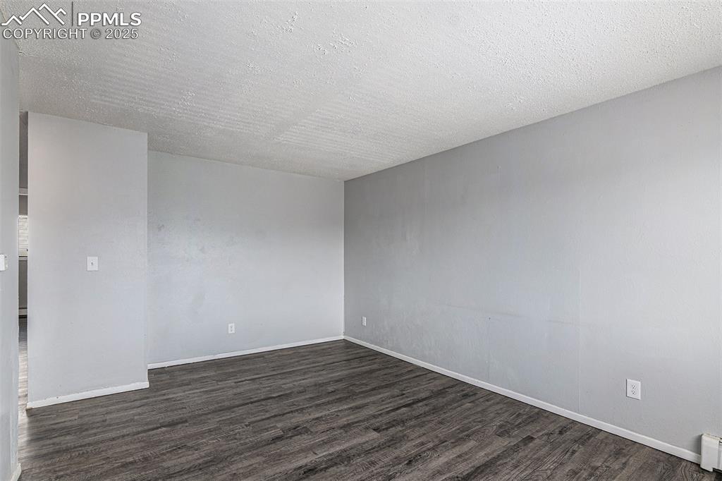 Image 7 of 18: Unfurnished room with a textured ceiling, dark wood finished floors, and a 