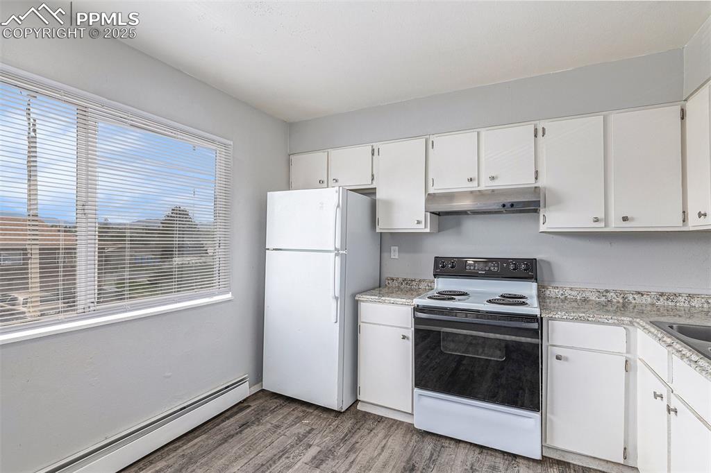 Image 8 of 18: Kitchen with white appliances, a baseboard radiator, light countertops, and