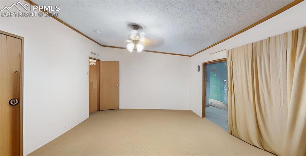 Image 19 of 31: Empty room with a textured ceiling, crown molding, light carpet, and a ceil