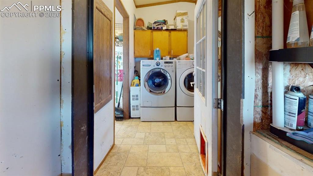 Image 29 of 31: Laundry area with light stone finish flooring and cabinet space