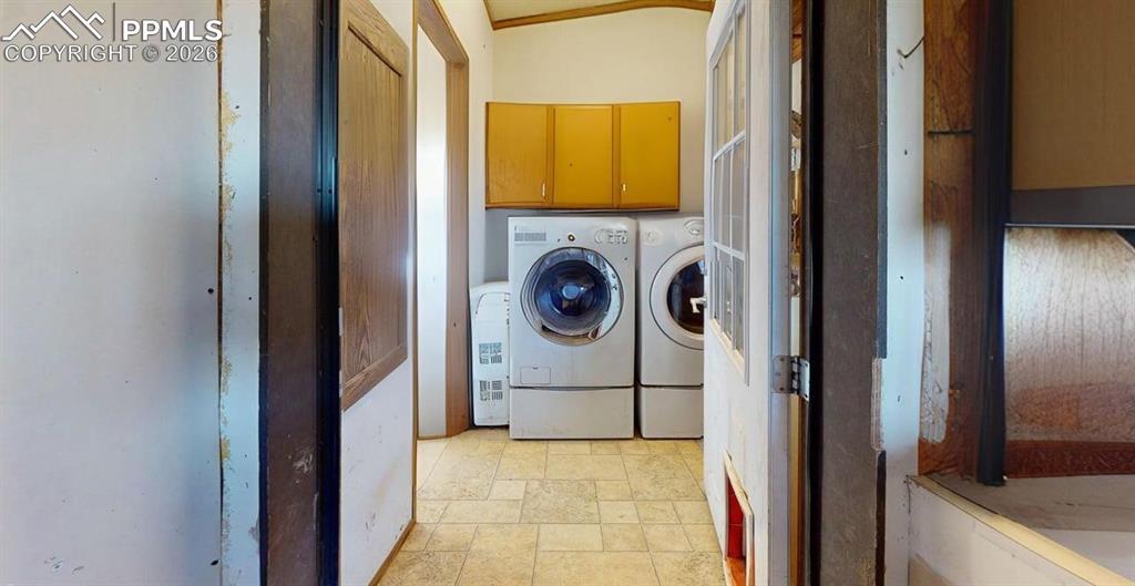 Image 30 of 31: Laundry room with light stone finish floors, cabinet space, and independent