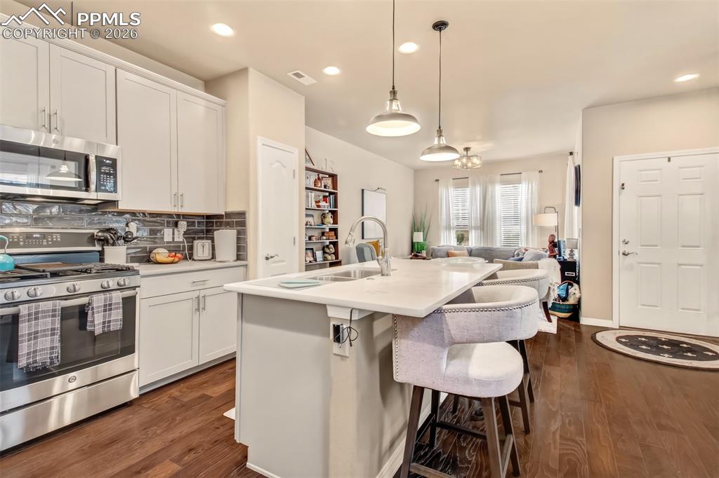 Image 11 of 32: Open concept kitchen with island, breakfast bar, stainless steel appliances