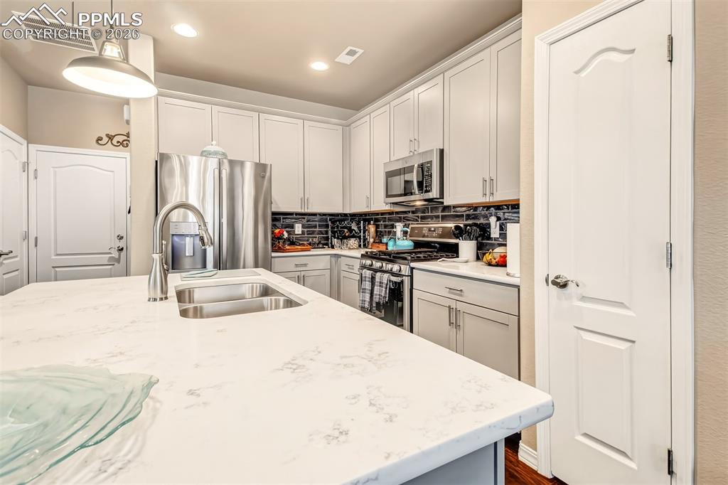 Image 12 of 32: Open concept kitchen with island, breakfast bar, stainless steel appliances
