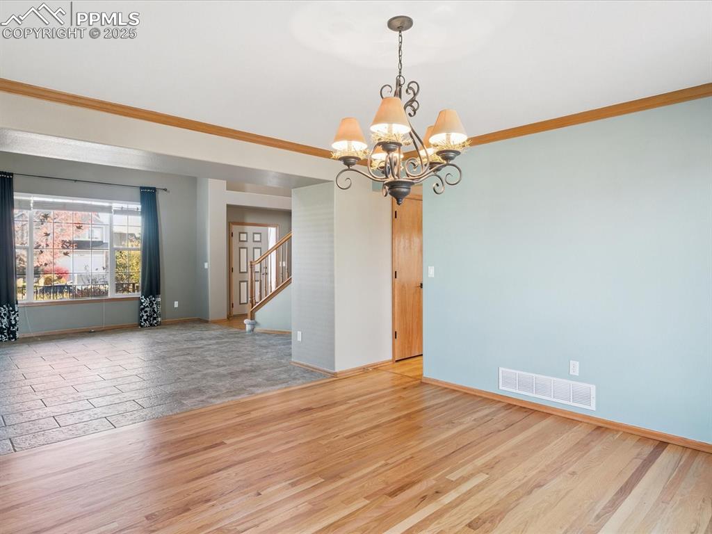 Image 16 of 45: Unfurnished room with light wood-type flooring, crown molding, a chandelier