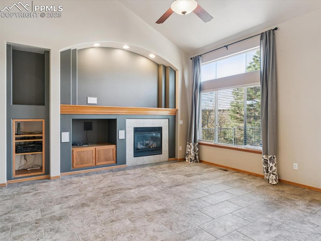 Image 22 of 45: Unfurnished living room with built in shelves, a tiled fireplace, a ceiling