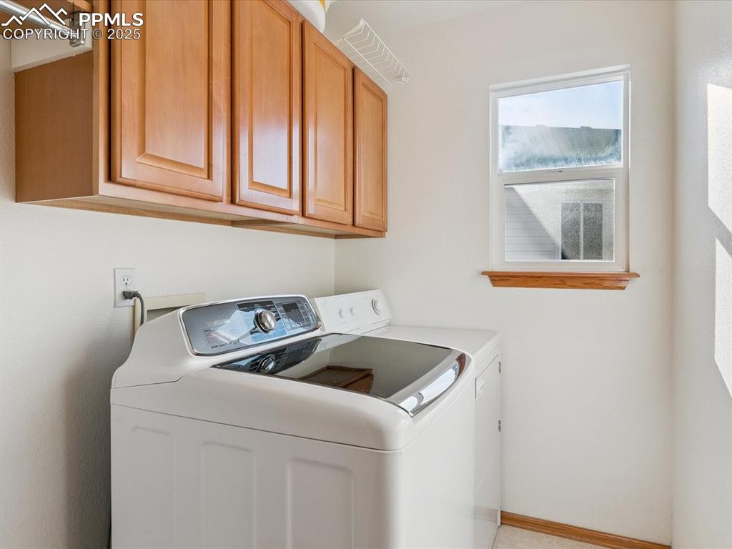 Image 26 of 45: Laundry room featuring cabinet space and separate washer and dryer