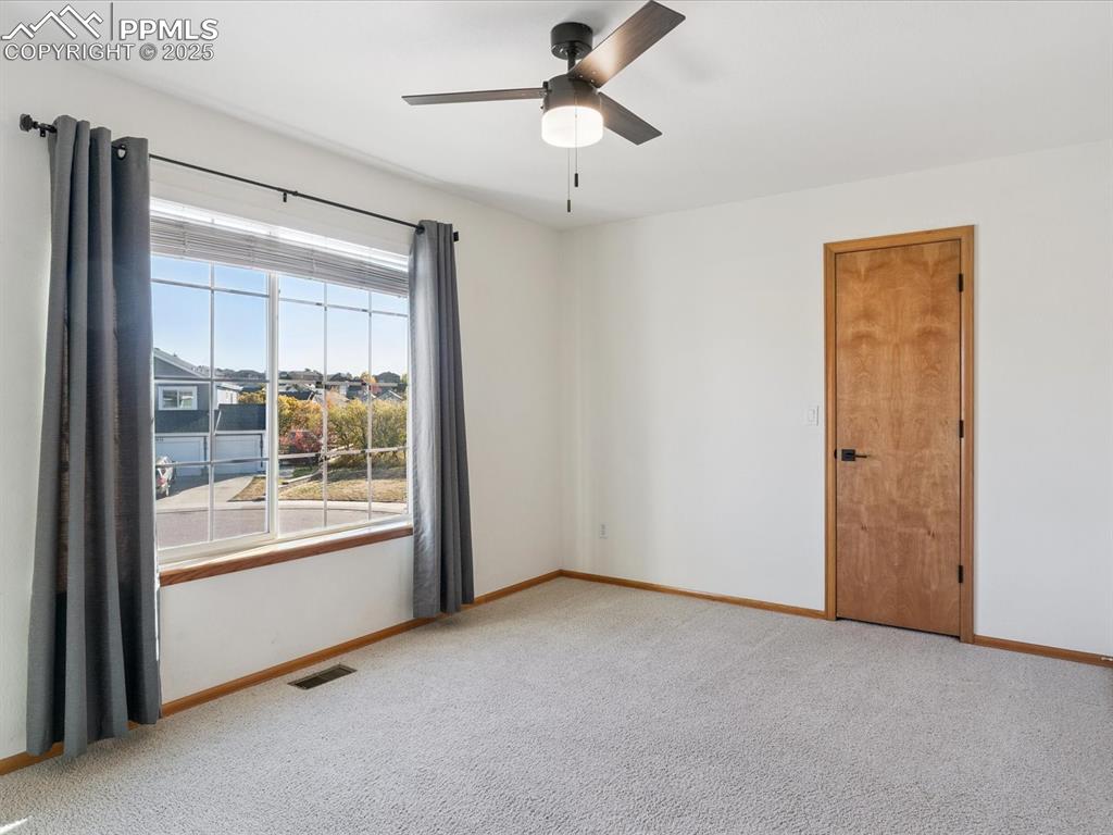 Image 34 of 45: Empty room with light colored carpet and a ceiling fan