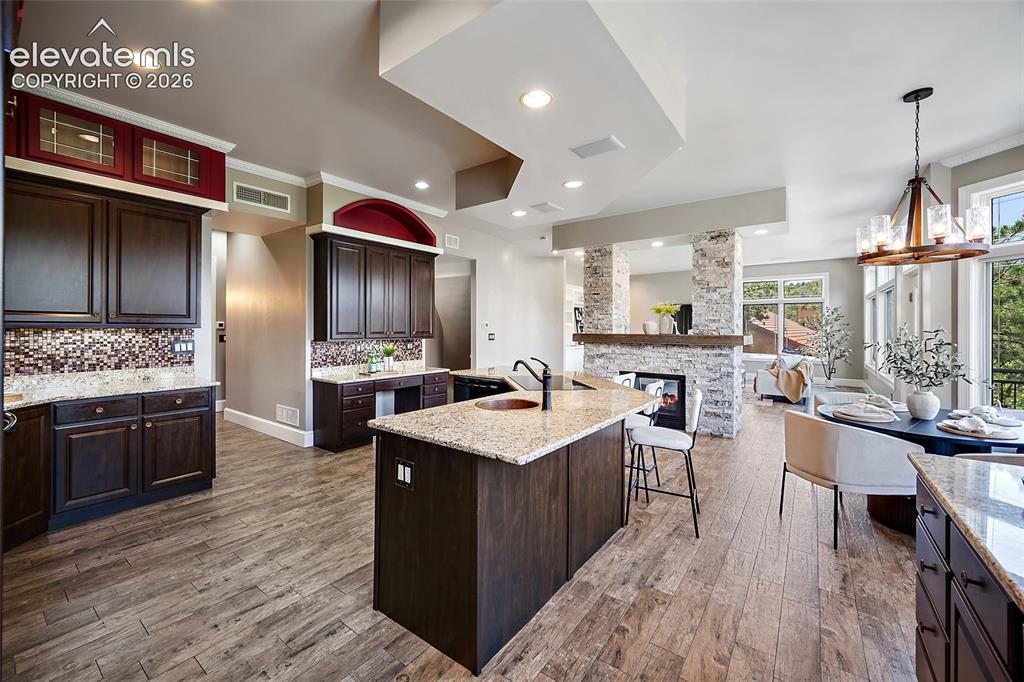 Image 10 of 50: Open-concept kitchen and dining area featuring wood-finish flooring, dark w