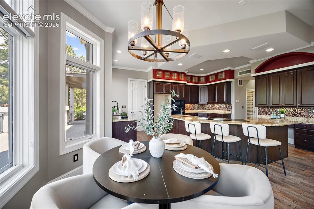 Image 11 of 50: Open-concept kitchen and dining area featuring dark wood cabinetry, granite