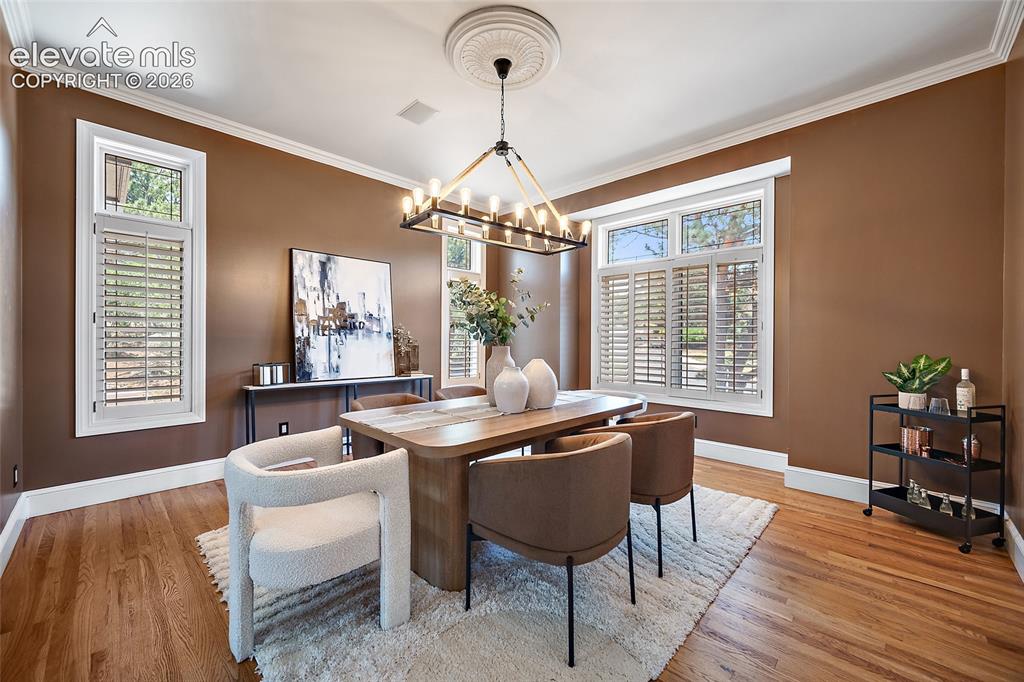 Image 14 of 50: Formal dining area featuring rich wall color and hardwood flooring