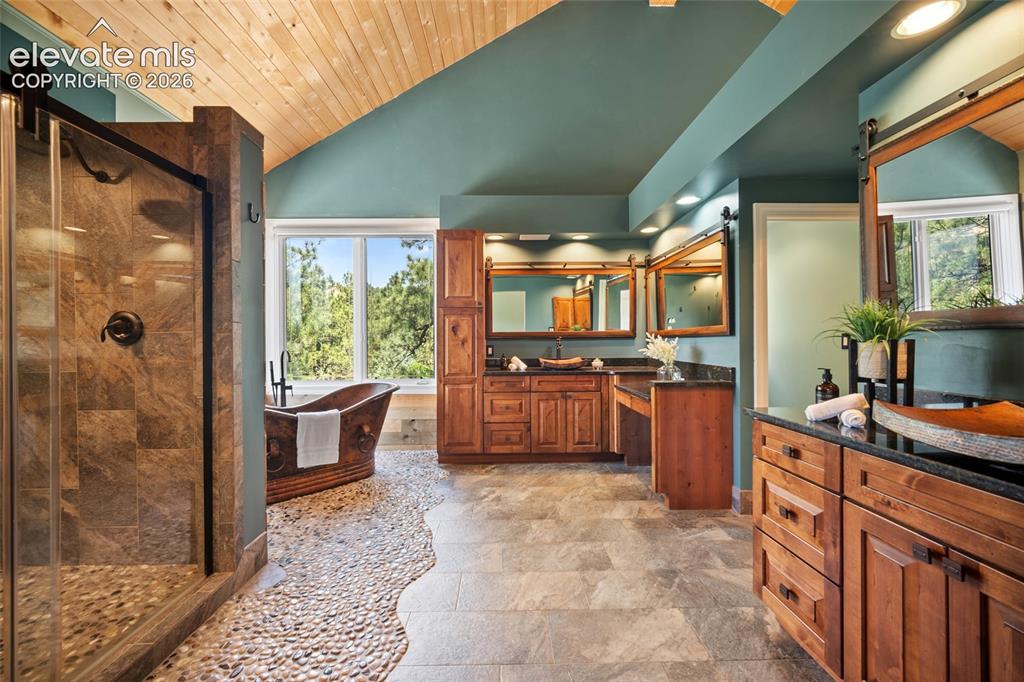 Image 20 of 50: Spacious bathroom featuring a freestanding soaking tub, dual vanities with 