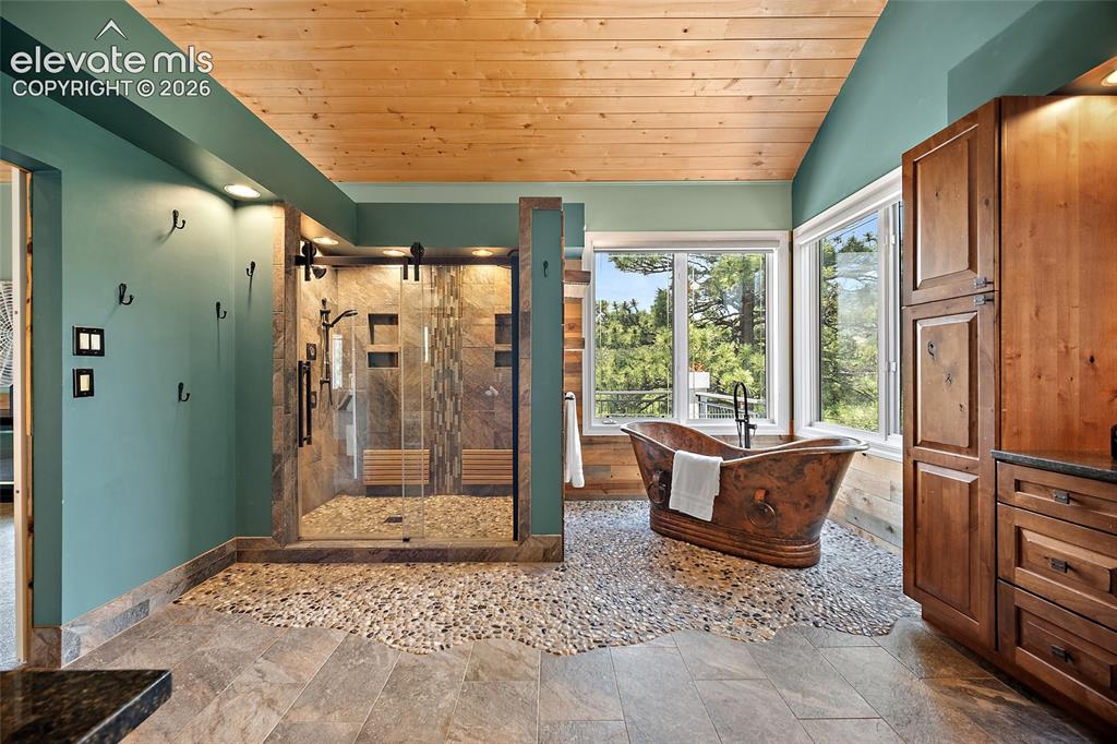 Image 21 of 50: Spacious bathroom featuring a freestanding copper soaking tub, a large glas