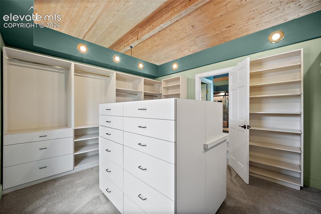 Image 22 of 50: Expansive custom closet featuring a central island with multiple drawers, b