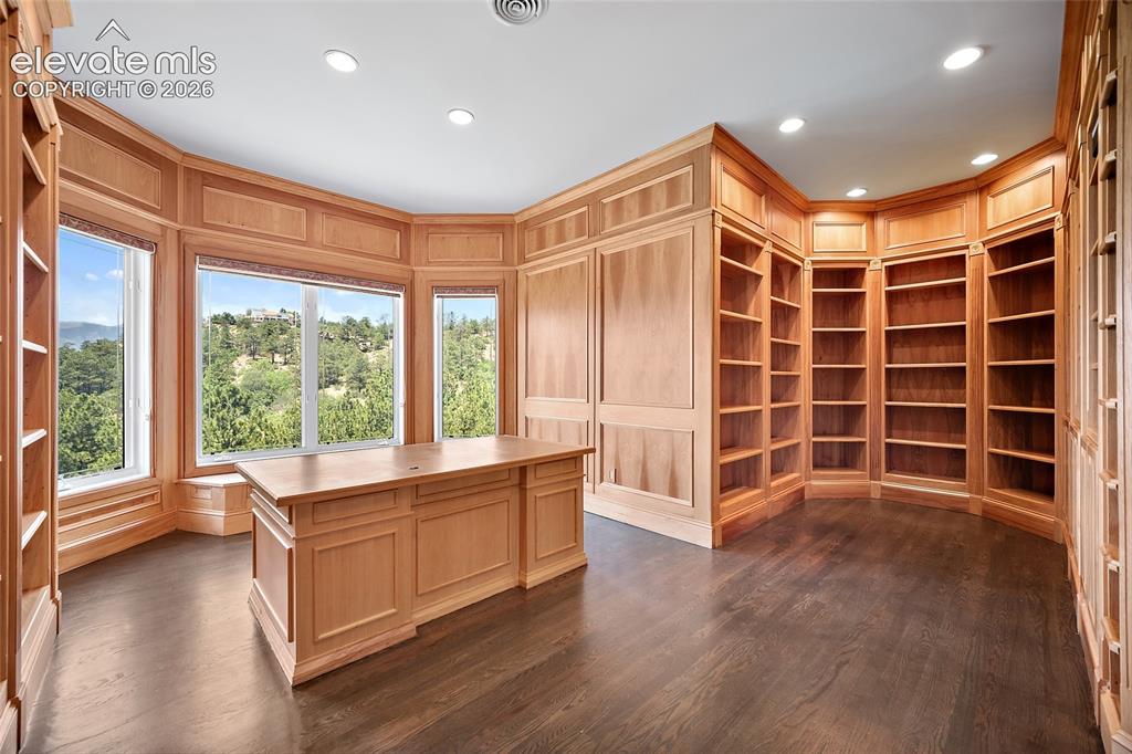 Image 24 of 50: Hardwood flooring complements extensive built-in shelving and custom wood p