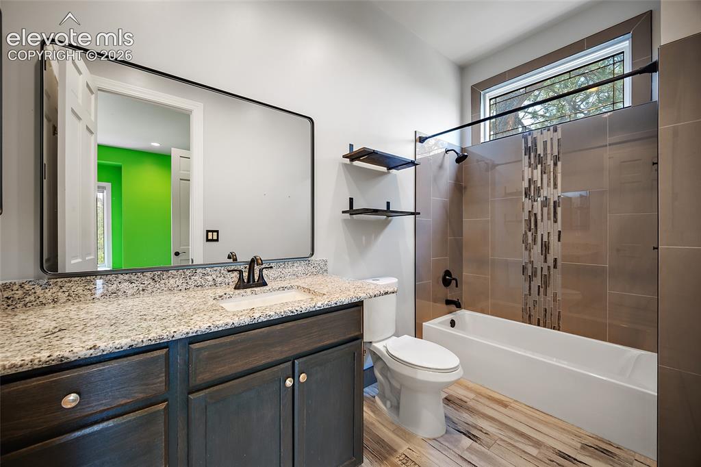 Image 26 of 50: Bathroom featuring a dark wood-finish vanity with a granite countertop, a r