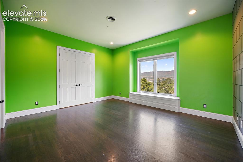 Image 27 of 50: Vibrant green walls with white trim throughout, dark wood-finish flooring, 
