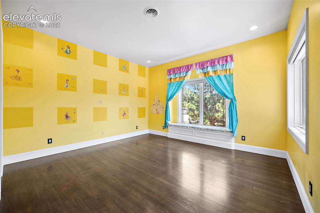Image 29 of 50: Spacious interior with dark wood-finish flooring, bright yellow walls, and 