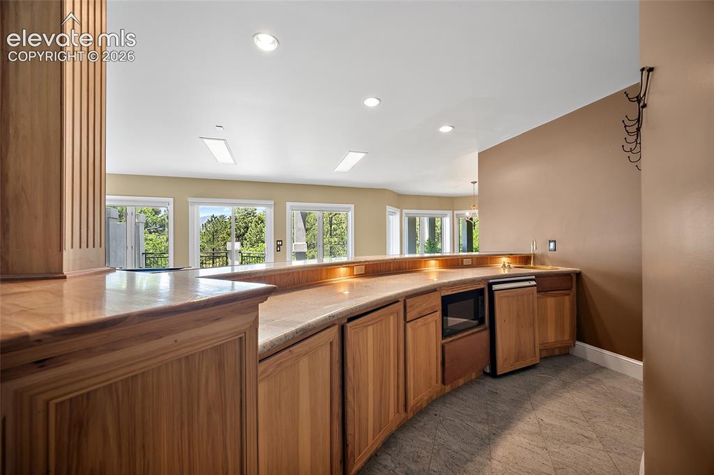 Image 32 of 50: Curved wood-finish bar featuring an integrated microwave, built-in mini-fri