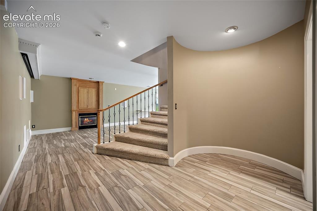 Image 35 of 50: Finished lower level featuring wood-finish flooring, a built-in fireplace w