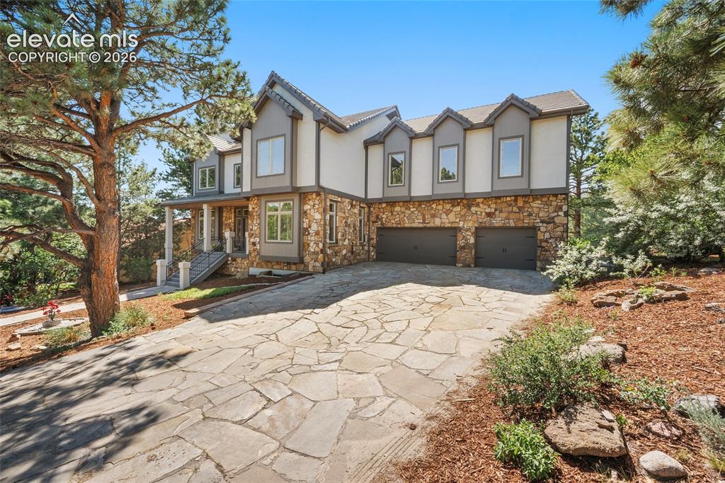 Image 4 of 50: Stone and stucco exterior with multiple gables and a multi-car garage