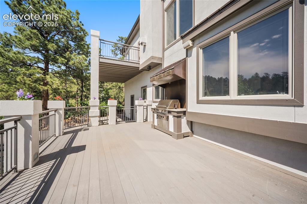 Image 42 of 50: Spacious composite deck with dark metal railings, an integrated outdoor gri