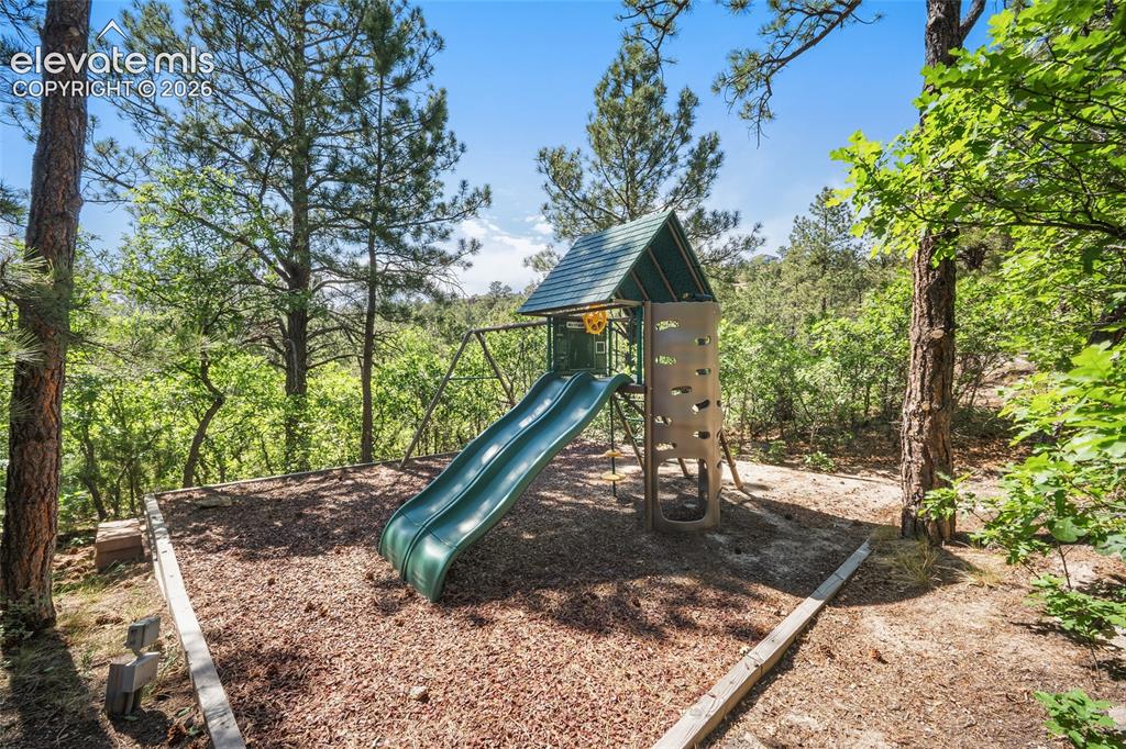 Image 43 of 50: Outdoor play structure featuring a slide, climbing wall, and elevated platf