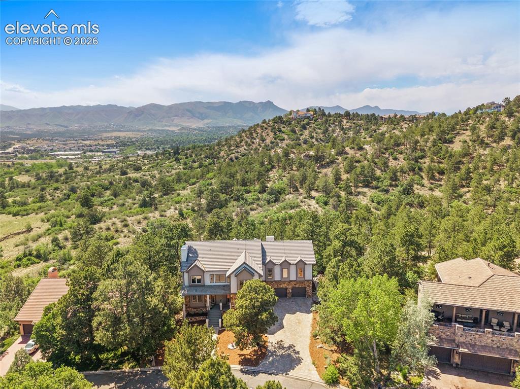 Image 47 of 50: Multi-level property nestled into a treed hillside with a mountain backdrop