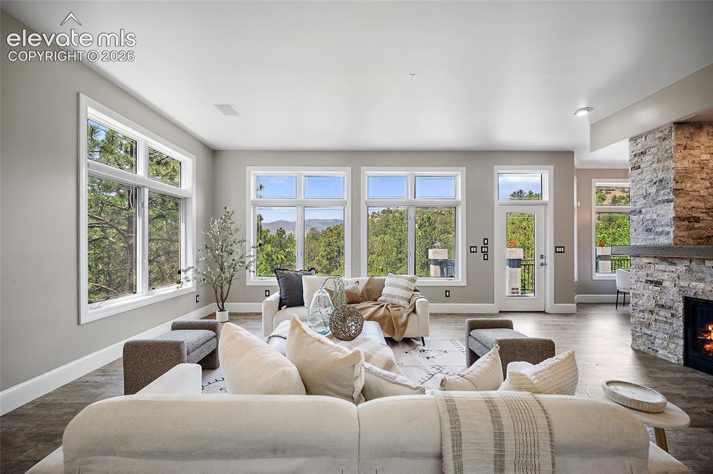 Image 7 of 50: Expansive living area featuring multiple large windows, wood-finish floorin