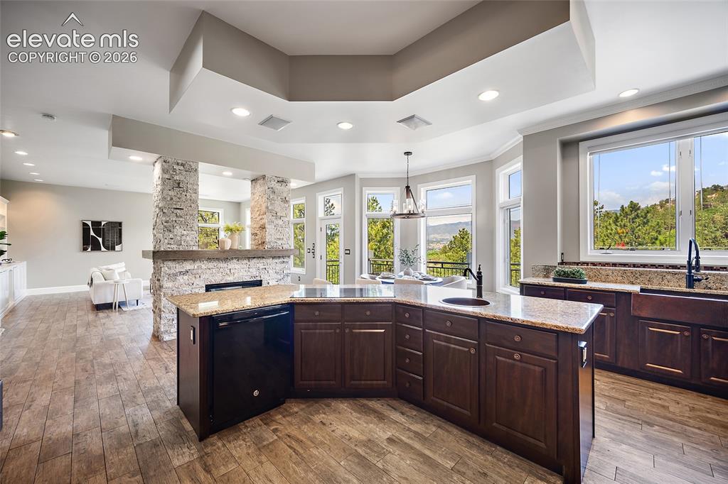 Image 9 of 50: Open-concept kitchen featuring wood-finish flooring, dark wood cabinetry, a