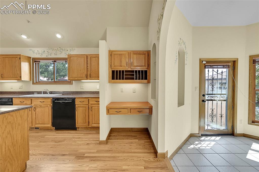Image 12 of 30: Kitchen with dishwasher, dark countertops, light wood-style floors, and bro