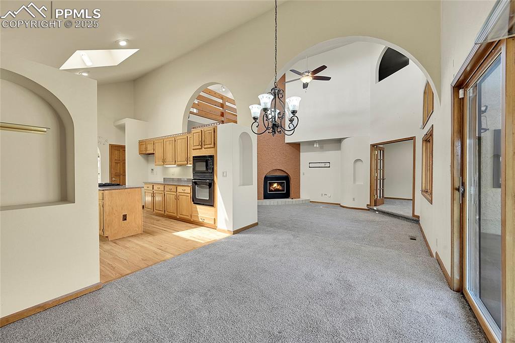 Image 13 of 30: Unfurnished living room featuring light colored carpet, arched walkways, hi