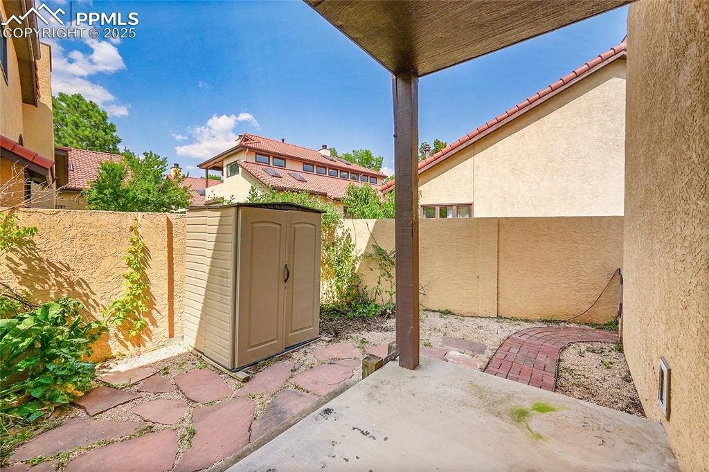 Image 18 of 30: Fenced backyard featuring a storage unit and a patio area