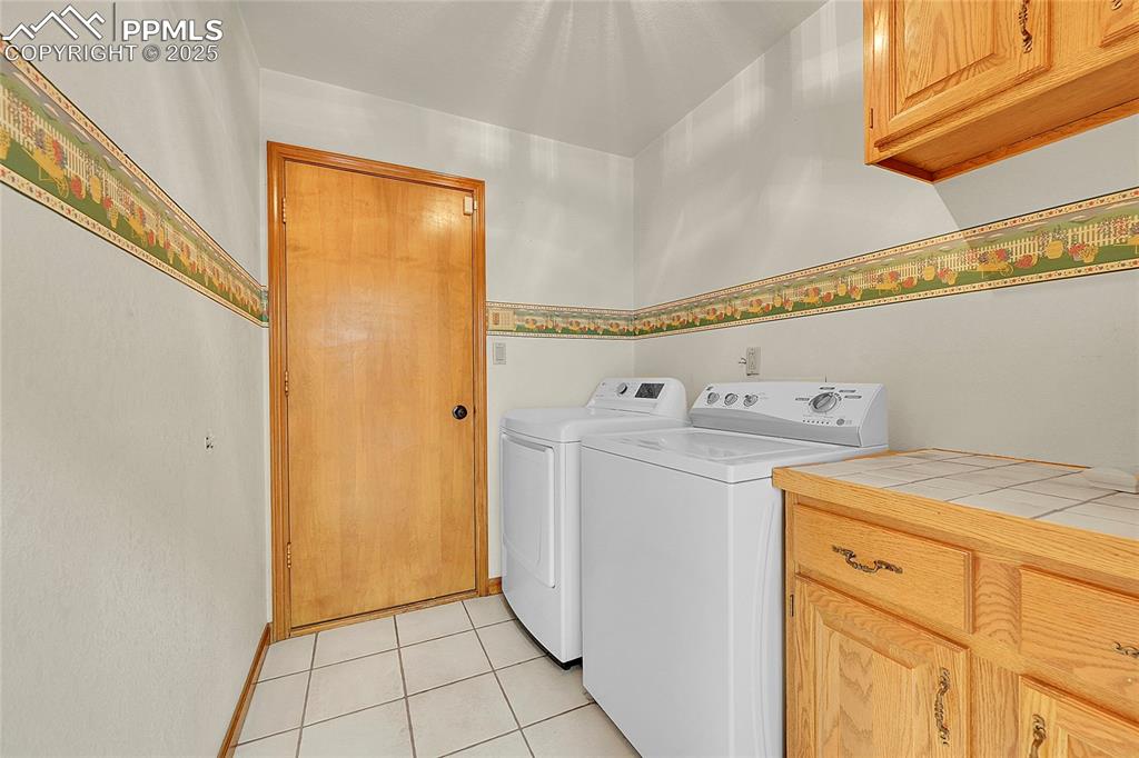 Image 19 of 30: Laundry area featuring light tile patterned floors, washer and dryer, and c