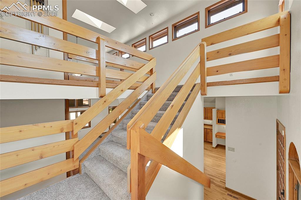Image 21 of 30: Stairway featuring a high ceiling and wood finished floors