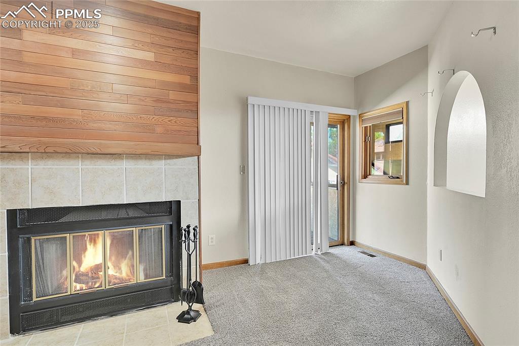 Image 23 of 30: Unfurnished living room with carpet flooring and a tile fireplace
