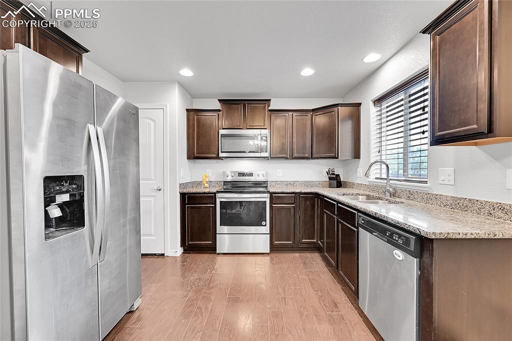 Image 12 of 29: Kitchen with a sink, stainless steel appliances, light wood-style flooring,