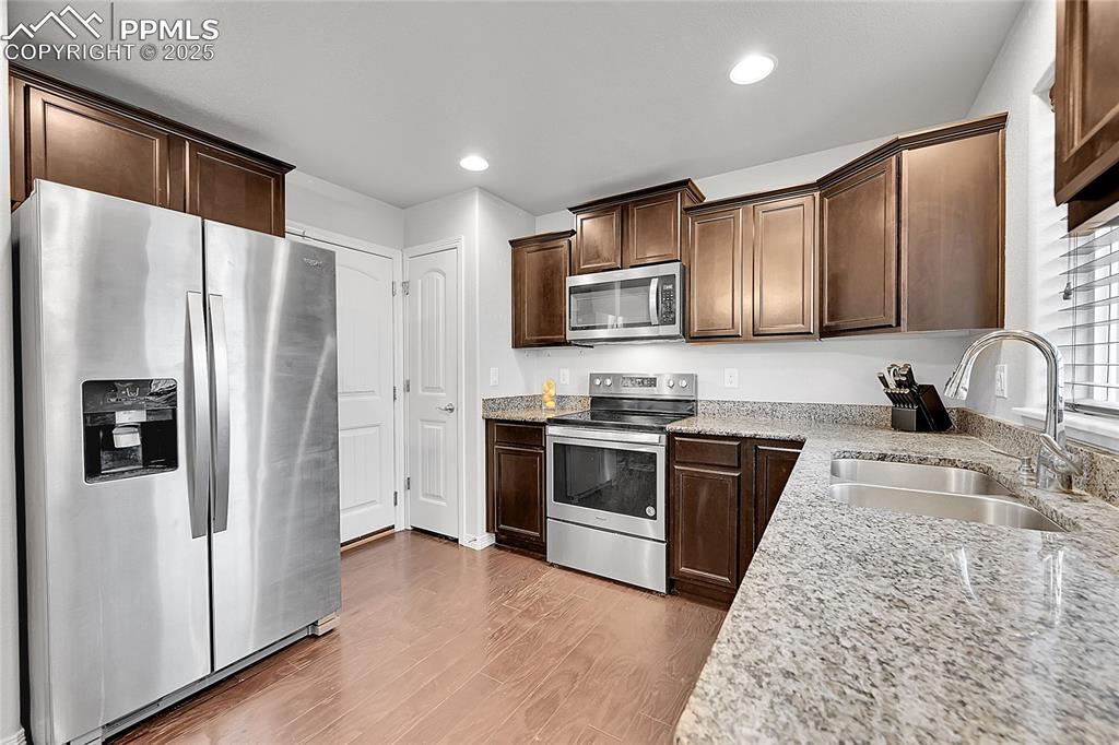 Image 13 of 29: Kitchen with dark brown cabinetry, appliances with stainless steel finishes